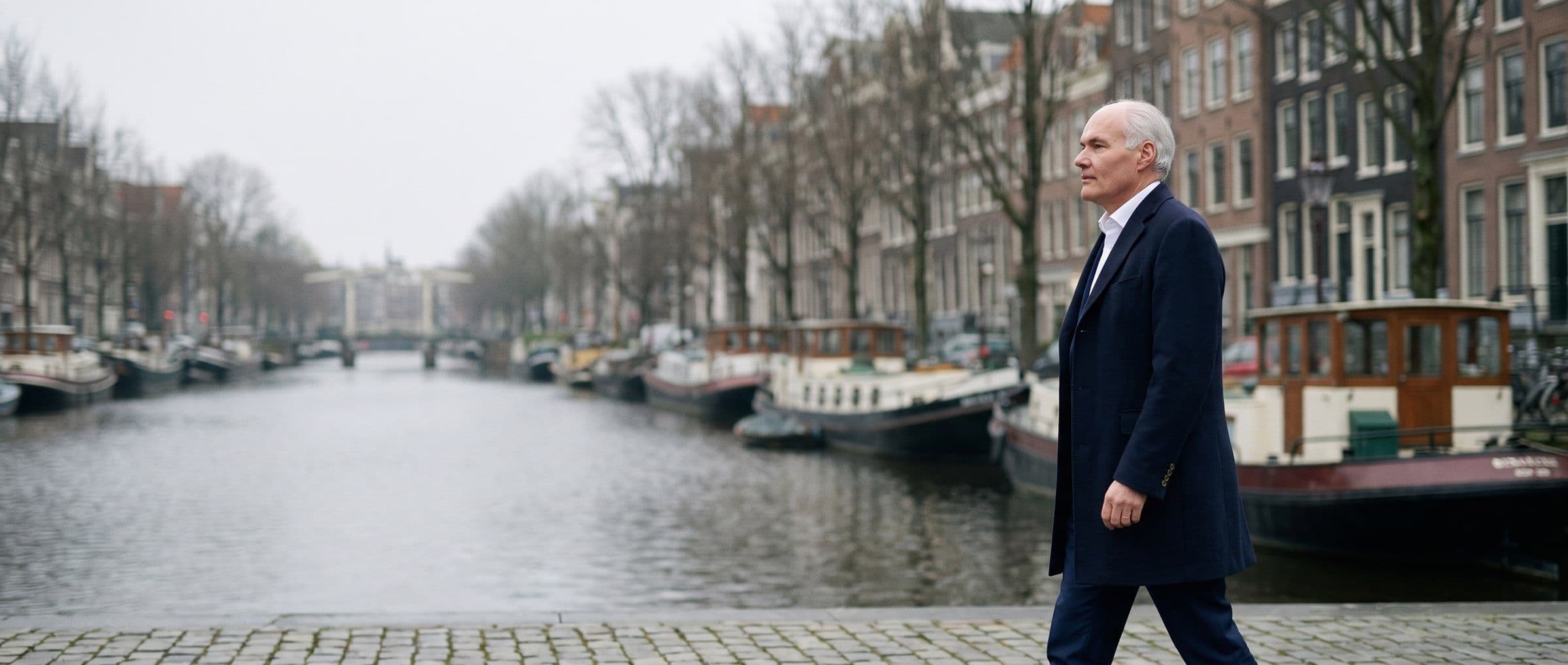 Mr. Dr. Paul Bavelaar LL.M wandelt langs een Amsterdamse gracht met woonboten