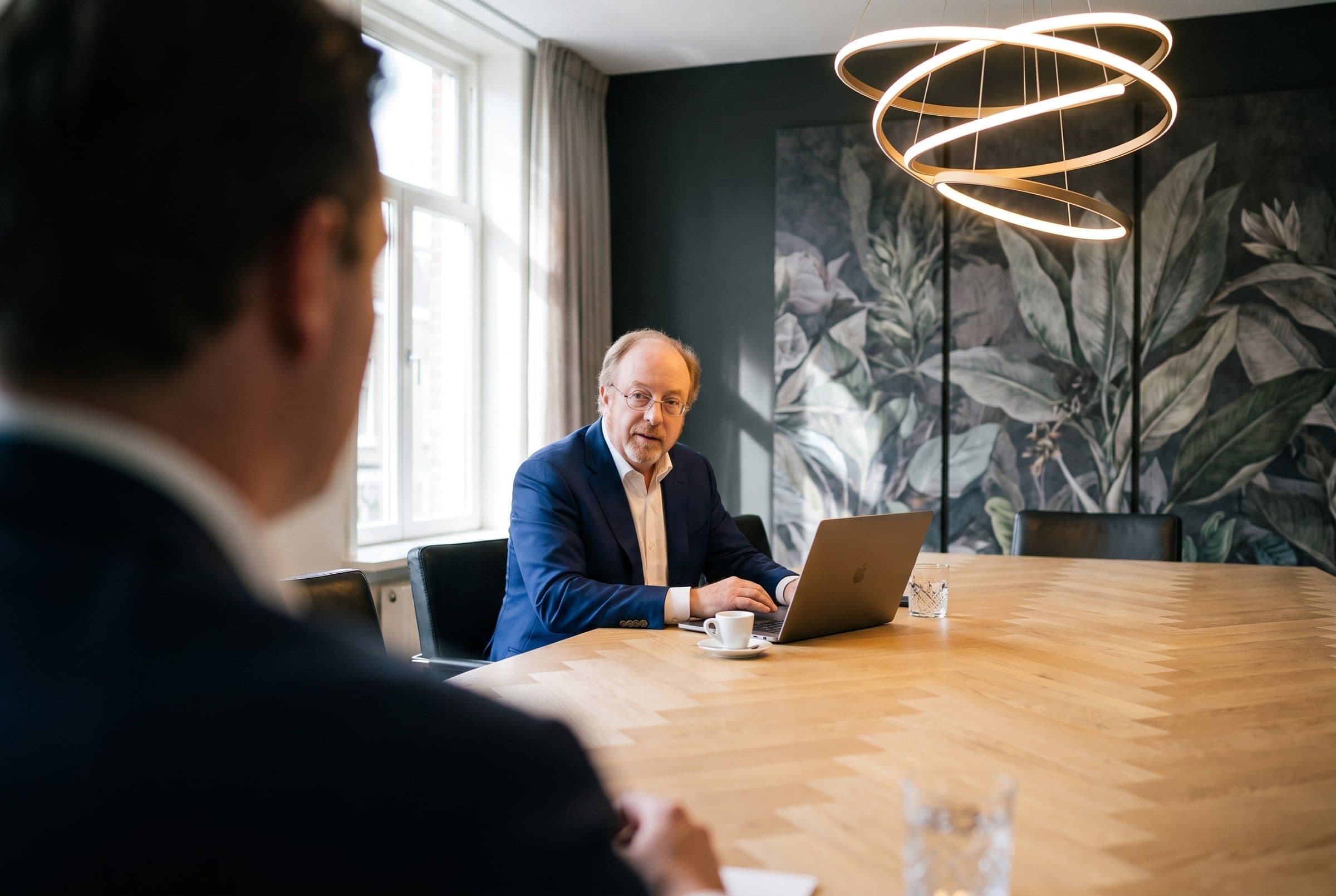 Vergadering met een cliënt aan een lange houten tafel in de vergaderzaal