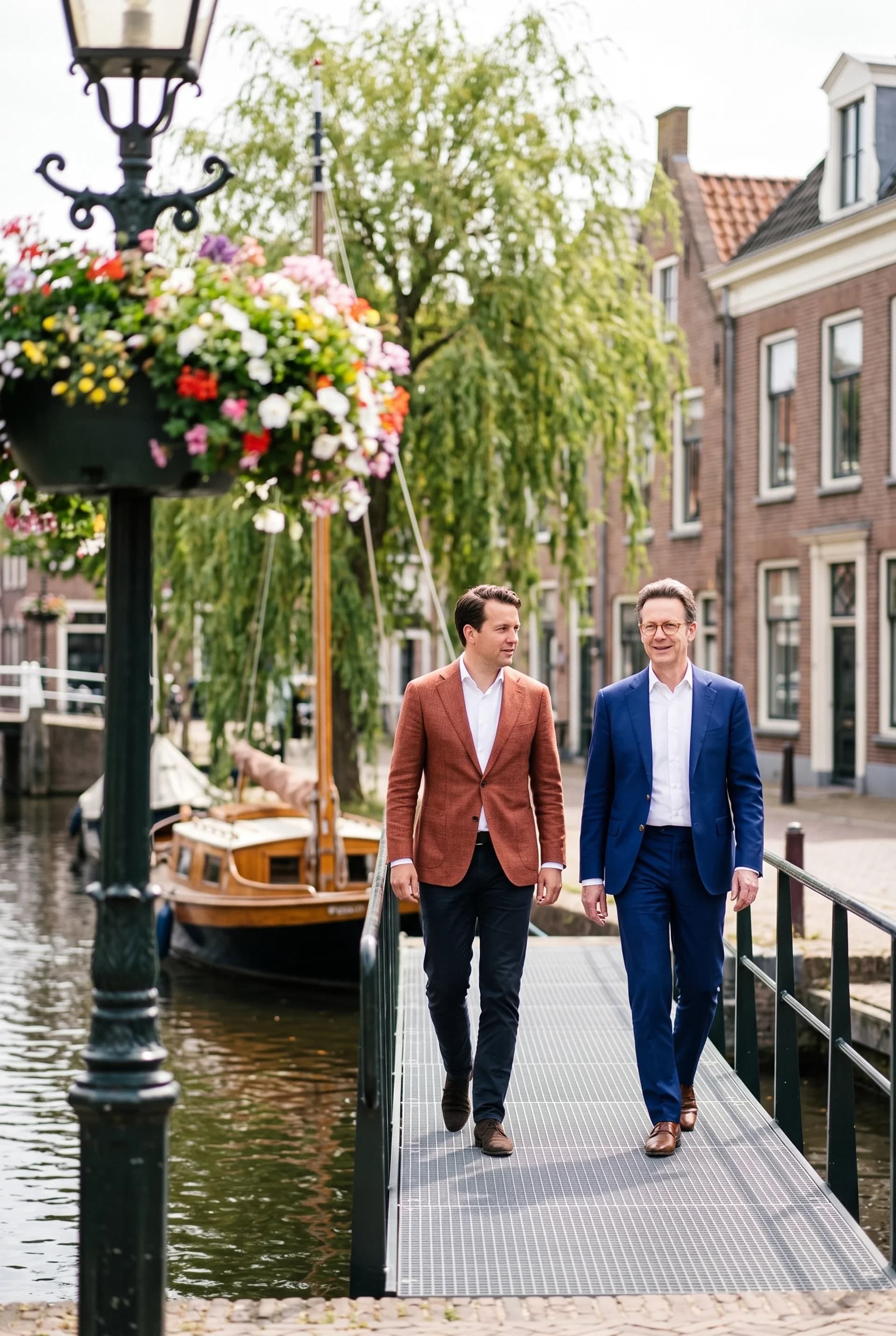 Twee advocaten in gesprek op een loopbrug langs een gracht met bloembakken