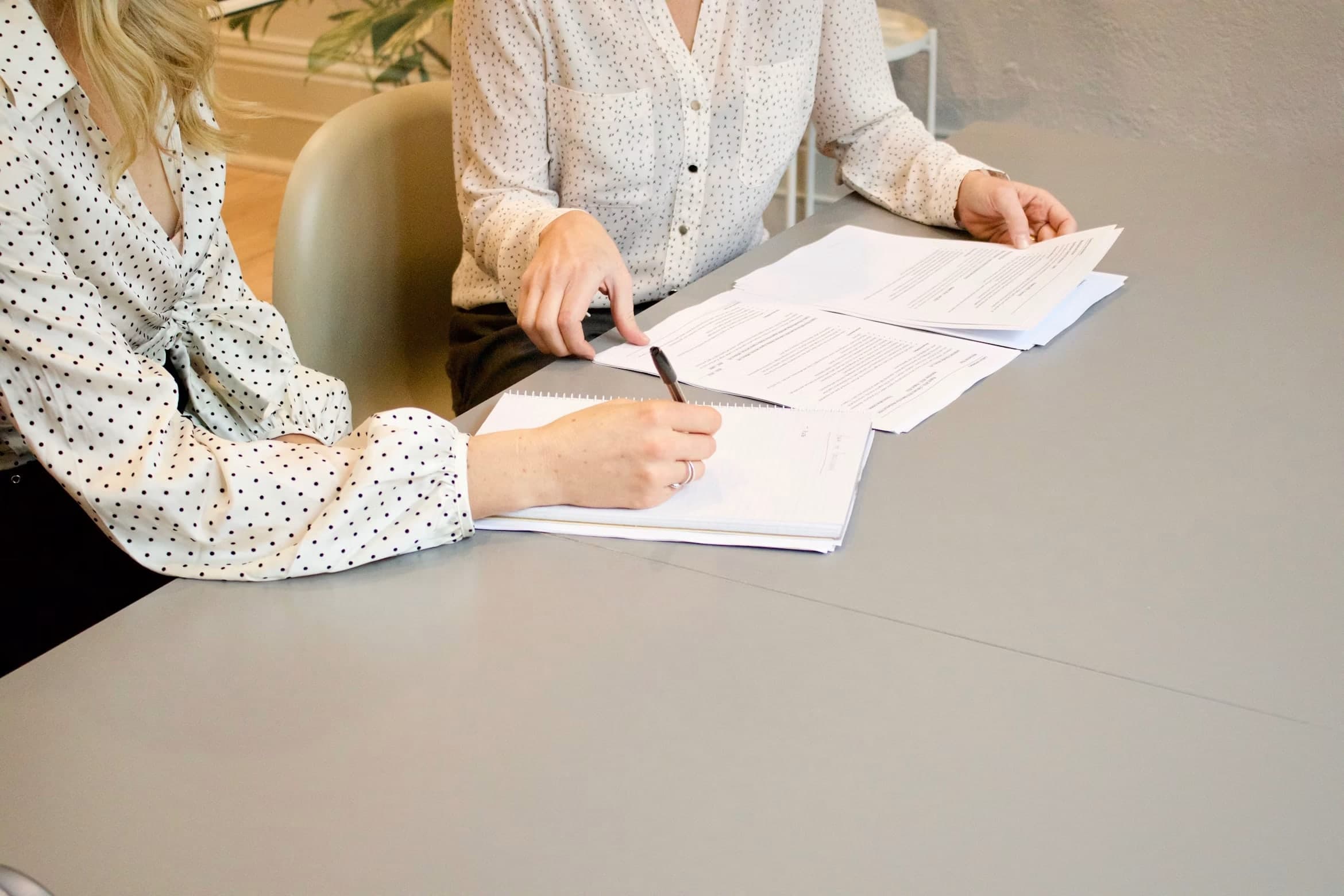 Twee zakenvrouwen nemen een contract door en ondertekenen het